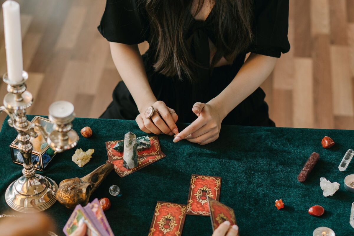 Cartas de tarot dispostas sobre uma mesa de veludo verde, à luz de castiçais