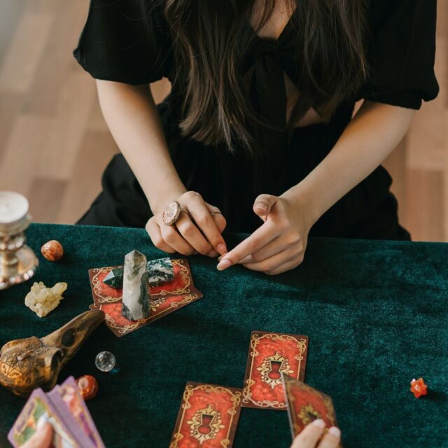 Cartas de tarot dispostas sobre uma mesa de veludo verde, à luz de castiçais