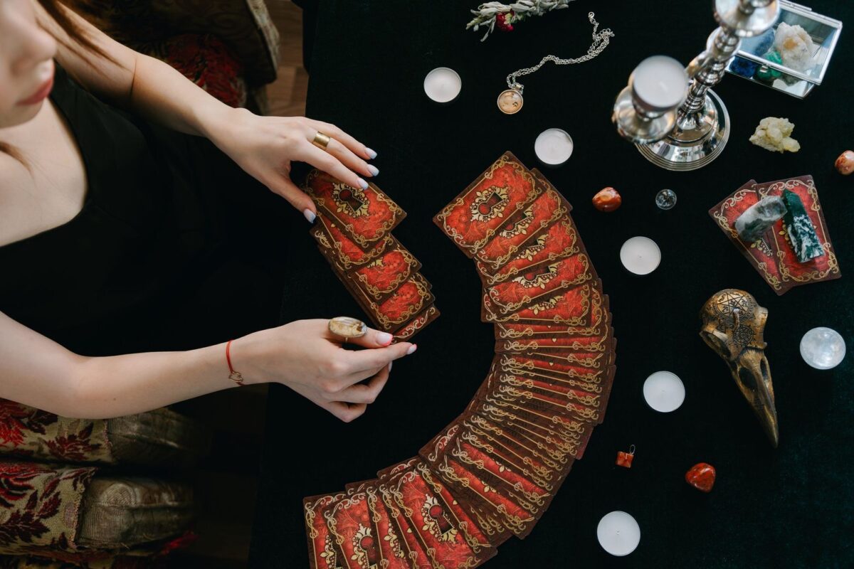 Baralho de tarot aberto em leque sobre pano escuro, com cristais em volta