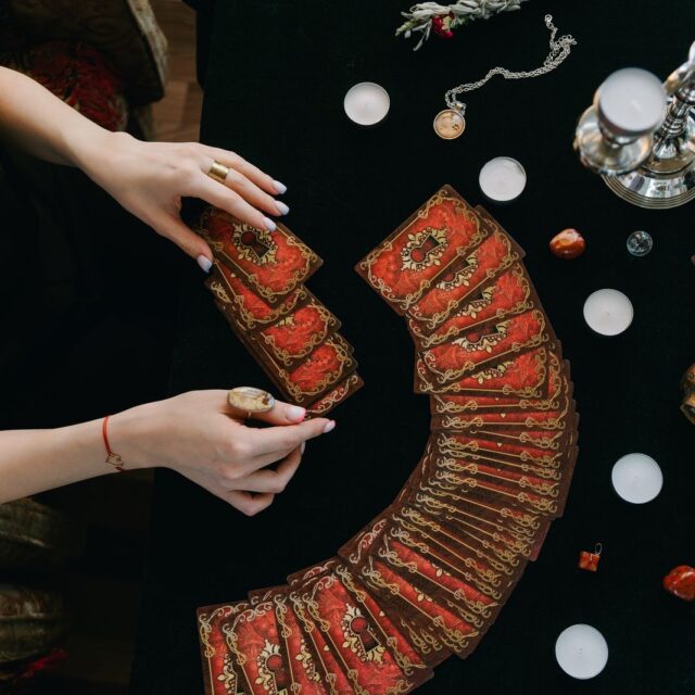 Baralho de tarot aberto em leque sobre pano escuro, com cristais em volta