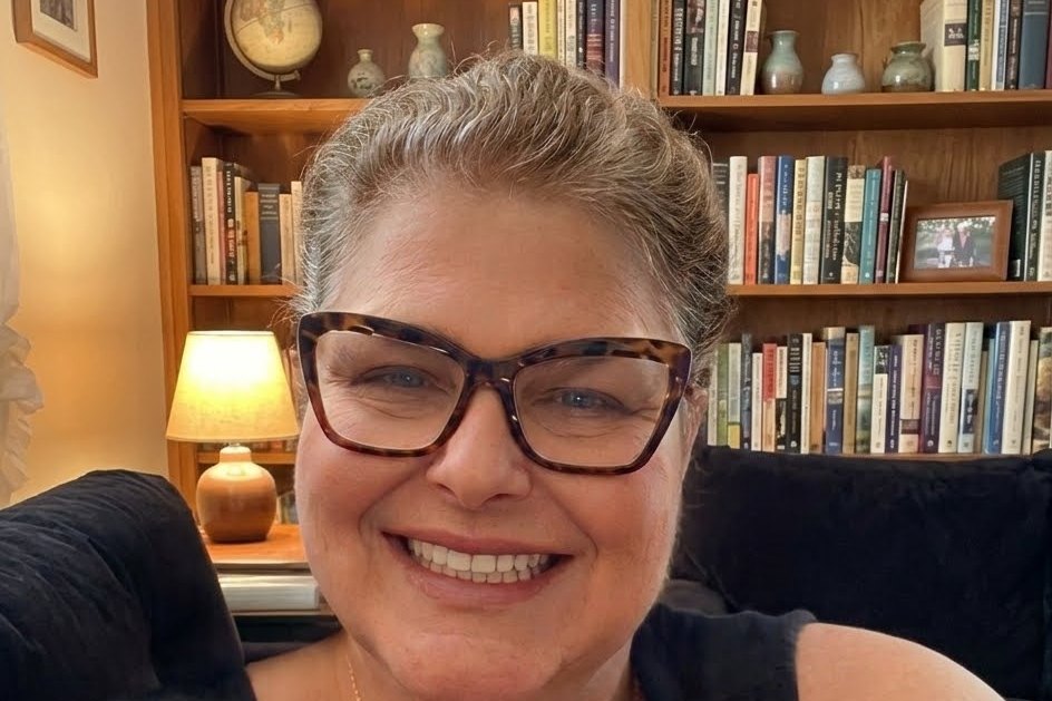 Barbara Mariah sorrindo, em frente a uma estante de livros