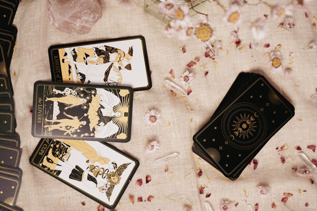 Cartas de tarot douradas sobre linho claro, com pétalas espalhadas