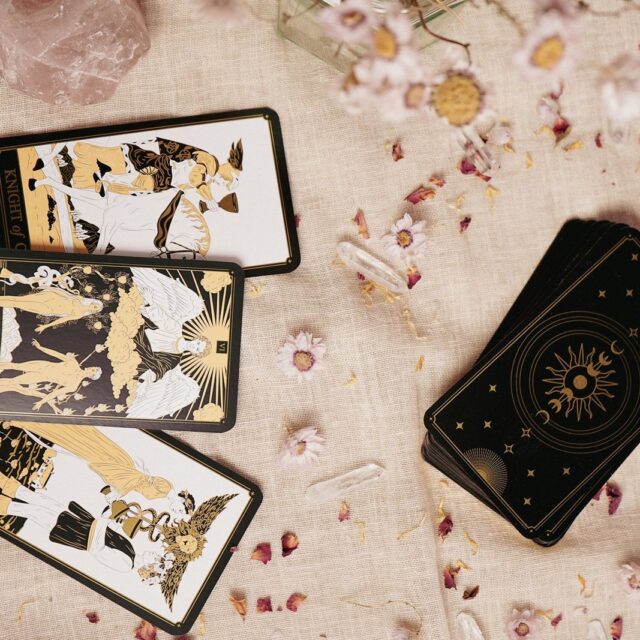 Cartas de tarot douradas sobre linho claro, com pétalas espalhadas
